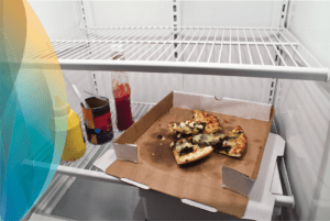 This is an image of a mainly empty fridge with some condiments as well as a partially eaten pizza in it